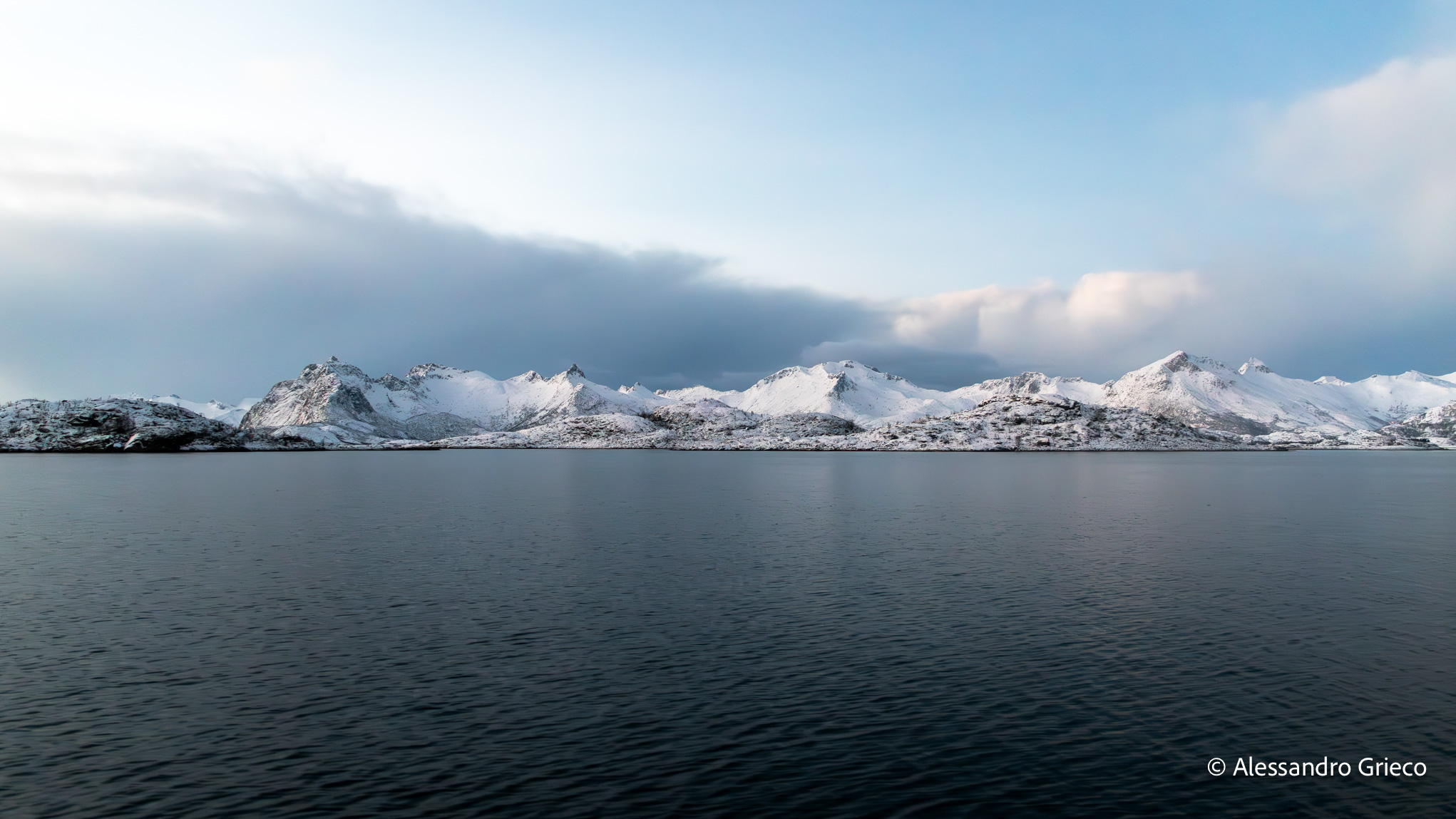 Approaching Trollfjord by boat, snow-capped peaks on calm water